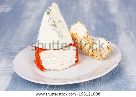Culinary luxurious cheese plate. Cheese variation on vintage plate on white and blue wooden background.