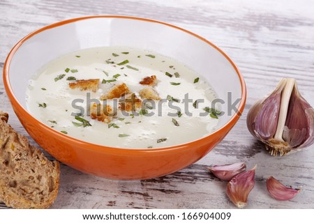 Garlic Cream Soup In Orange Bowl On White Wooden Background. Culinary Healthy Soup Eating, Rustic Country Style.