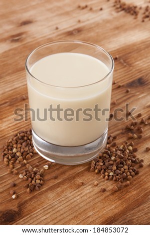 Vegan milk drinking. Buckwheat milk on wooden background. Delicious vegetarian and vegan eating.