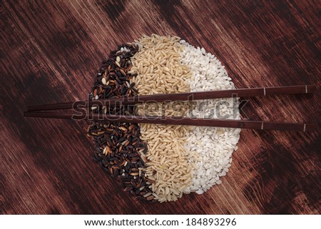 Rice variation of organic rice with chopsticks on dark wooden background. Healthy rice cooking concept.