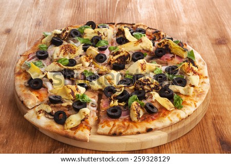 Delicious pizza with fresh herbs, olives on wooden background. Pizza eating.