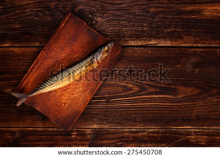 Smoked mackerel on wooden chopping board, on old vintage textured wooden table, top view. Vintage style fish with copy space.