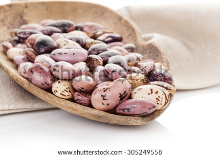 Pinto beans on wooden scoop on beige table cloth. Healthy eating, agriculture background.