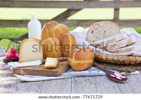 Traditional organic smoked cheese with fresh vegetables, milk and bread in background.