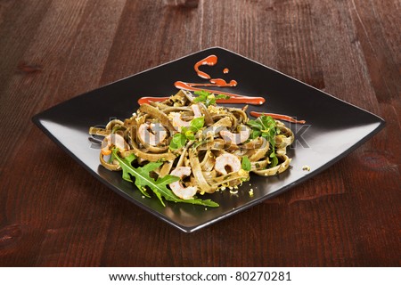 Luxurious pasta with shrimps on black plate on wooden table. Luxurious dining.
