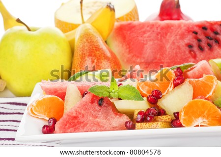 Delicious colorful fruit salad close up. Fruits in background. Light summer food.
