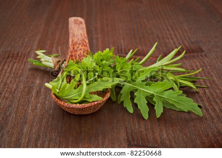 Fresh organic herbs on wooden spoon and wooden table. Aromatic culinary herbs mix. Parsley, roquette and rosemary.