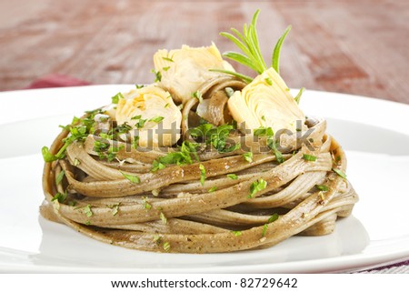 Pasta with artichoke hearts on white plate close up. Luxury culinary eating.