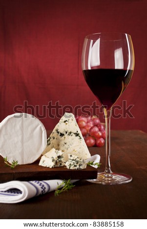 Traditional dark red wine background with blue  cheese and grapes on dark wooden background.