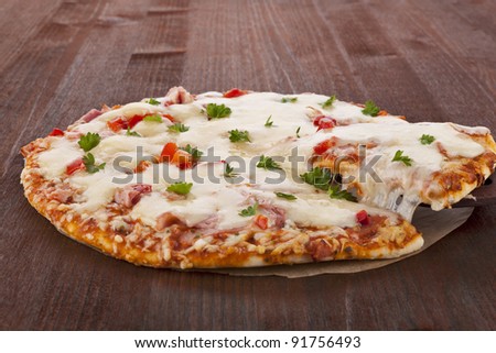 Delicious fresh hot pizza with melting cheese and fresh herbs, rustic style. Country style italian food.