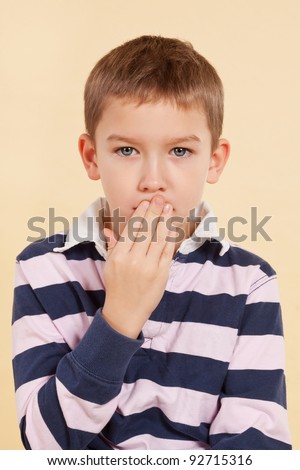 Young boy with black eye and hand over his mouth isolated. Domestic violence concept. Don\'t tell anyone. Psst