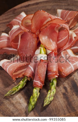 Prosciutto slices with asparagus. Traditional italian food background, rustic style.