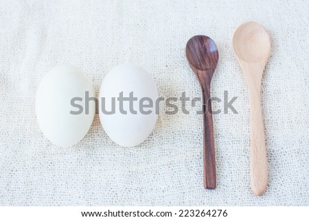 Salted eggs and wooden spoons on white fabric