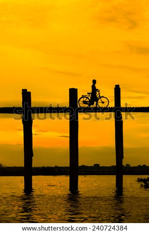 Silhouetted person with a bike on U Bein Bridge at sunset, Amarapura, Mandalay region, Myanmar