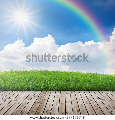 Green field under blue sky with sun beam. Wood floor