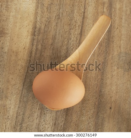 fresh brown eggs in wooden spoon on table.