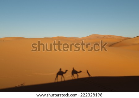Two Camel Riders Have Their Shadows Cast on Sand Dunes in Morocco
