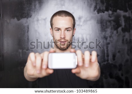 Men holding smartphone in hands and showing display, black t-shirt and background, studio shot
