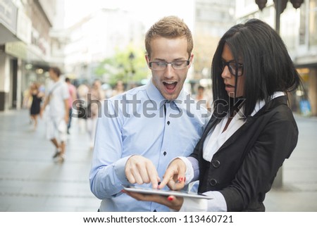 Businesspeople on street - man and woman with tablet computer