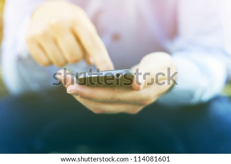 Man with smart phone on hand, blurred background