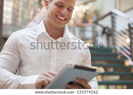 Businessman with tablet computer in hands, blurred background, modern business building