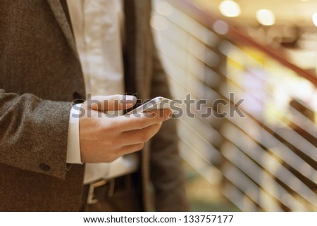 Smartphone in hand of businessman, blurred background, business building interior