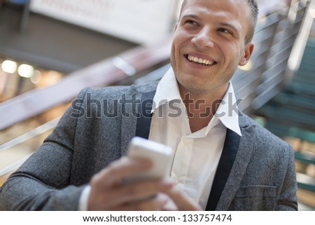 Men with smart phone on hand, blurred background, business building interior