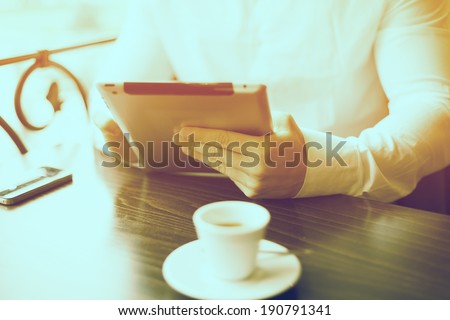 Man with tablet computer reading news at motning in cafe shop