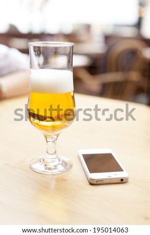 Beer and mobile phone on table