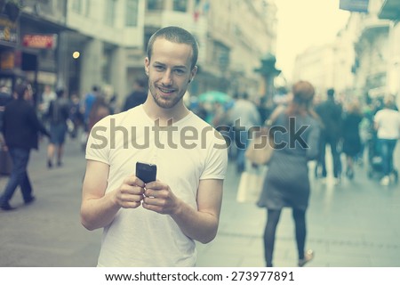 Smiling Man with mobile phone walking, background is blured city