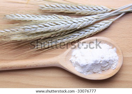 Grains of wheat and flour isolated on wooden background