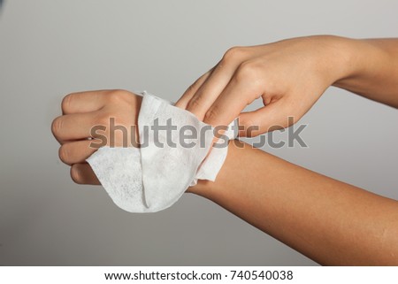 Young woman cleaning hands with wet wipes