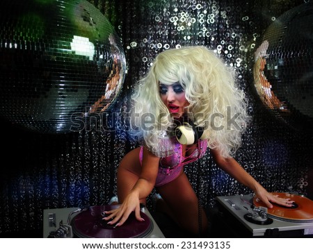 a beautiful sexy female drag artist djing and playing music in character in a disco/club setting