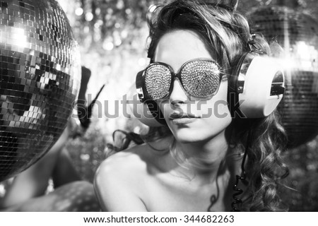 stunning sexy disco woman with crystal covered sunglasses poses on a bed, surrounded by disco balls