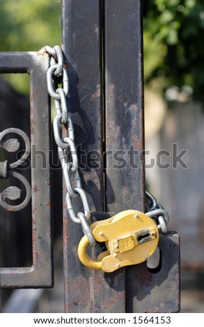 small yellow padlock and metal gate