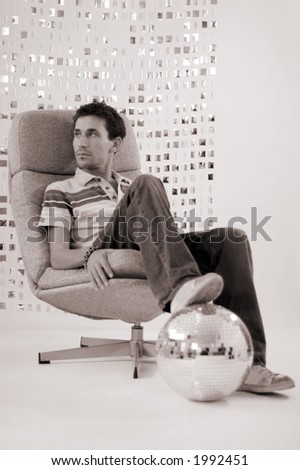 a man relaxes in a chair with foot on glitterball