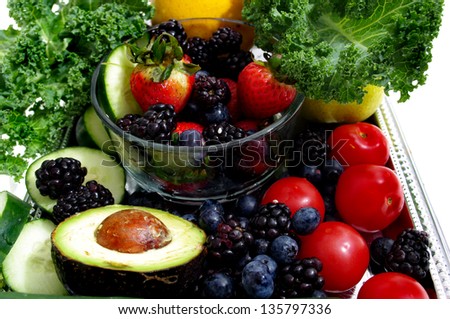 a group of garden fresh  organic vegetable and fruit including  leafy green  kale, blue   berries, red  tomato, and ripe avocado  .