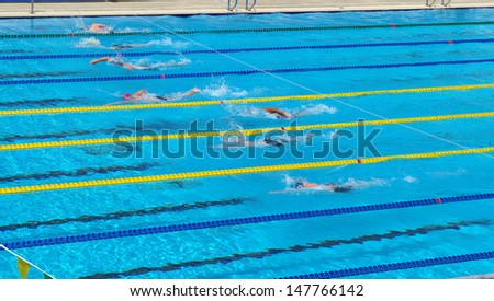 freestyle swimming race with swimmers racing in a pool . water sports in summer  activity .
