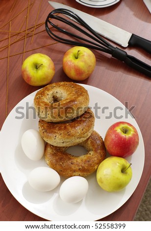 preparing breakfast ,  bagels eggs apples table food ingredient  with knife and eggbeater on table