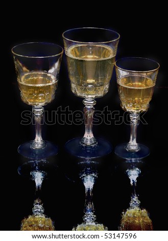 wine glasses with golden spirit beverages . dark background with reflection