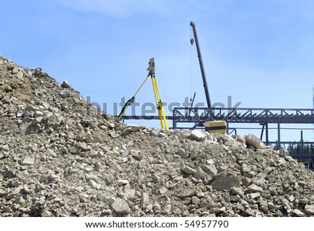 excavation pile of demolition debris with survey equipment on top and  scaffold in background