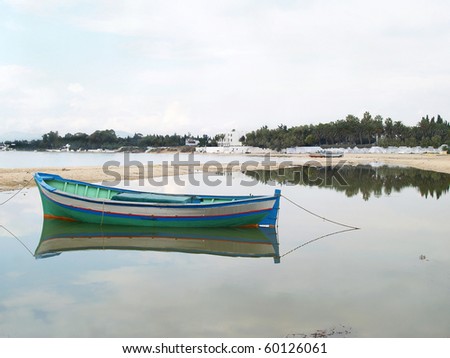 lone canoe on sandy beach and body of water, at hammamet city, tunisia, north africa.