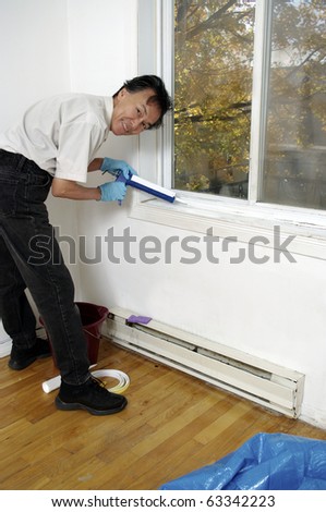 man using caulk-gun caulking  window sill to winterize insulate home