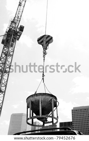 industrial crane hoisting concrete mixing container in inner city with urban infrastructure skyscrapers in the background