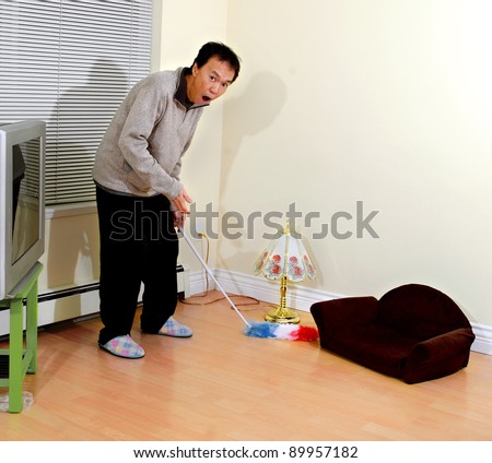 housekeeping man standing in a  room with tiny sofa. funny adult reaction with  emotion of surprise expression
