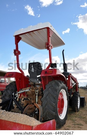 Red tractor against blue sky with clouds