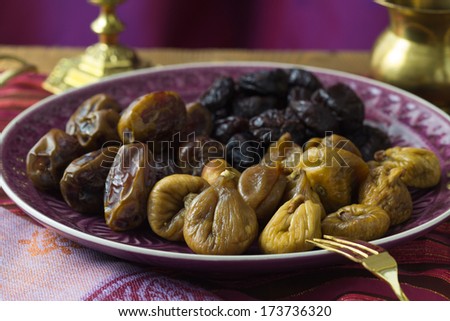 A selection of dried dates and figs on a purple serving plate