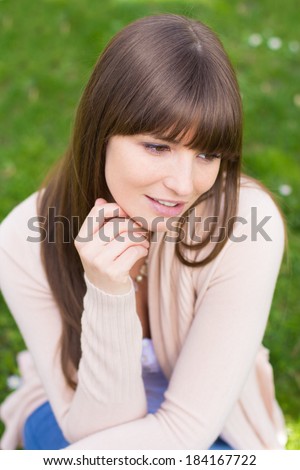 Young woman with hand on chin in pink cardigan sweater