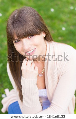 Satisfied young woman with hand on chin in pink cardigan sweater