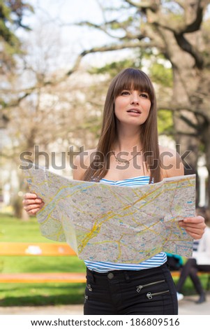 Happy young woman holding map in park